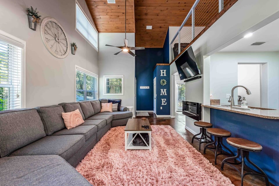 Living room with electric fireplace, smart TV, sound bar, large sofa. 