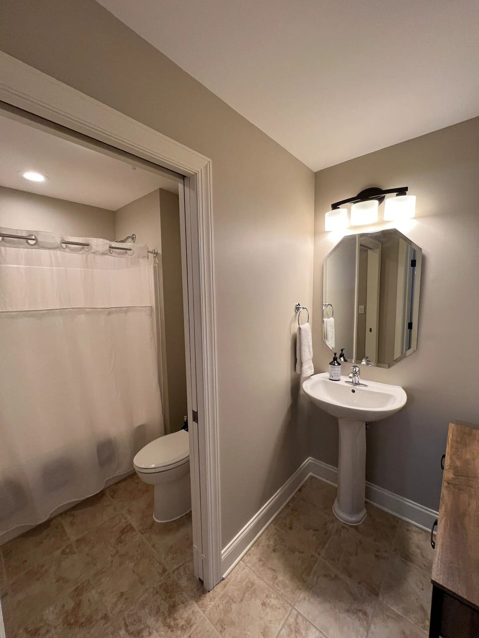 Guest Bathroom with tub/shower and toilet separated from sink by a pocket door