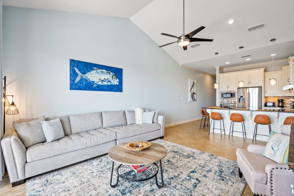 Extra long couch in a spacious living room, connected to kitchen area.