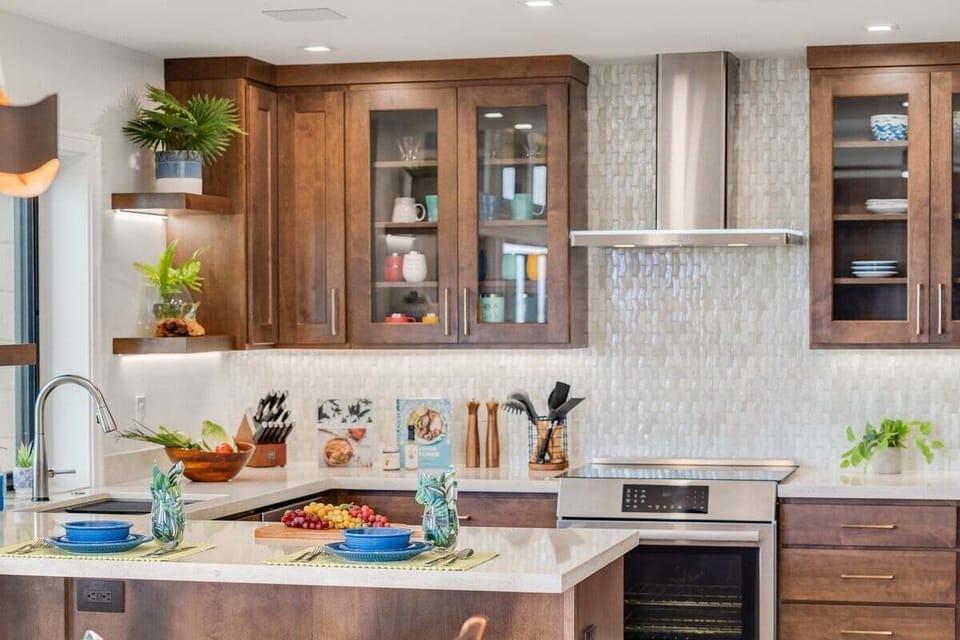 Modern kitchen with stainless Bosch appliances, stone countertops, warm wood cabinetry, and stylish open shelving.