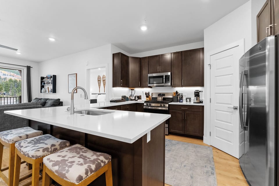 Your modern kitchen features sleek white quartz countertops, rich espresso cabinets, and stainless steel appliances perfect for preparing memorable meals.