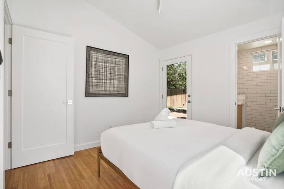 Queen bedroom with luxury hotel linens, bathroom, and work desk