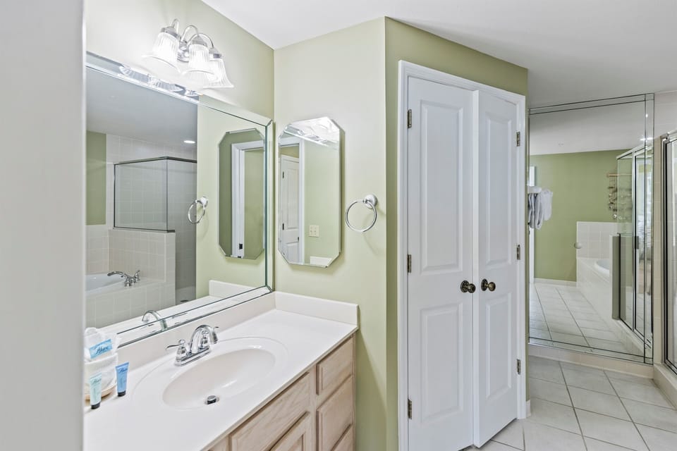 Step into your serene bathroom oasis with soothing green walls, dual vanities, and a spacious glass shower.