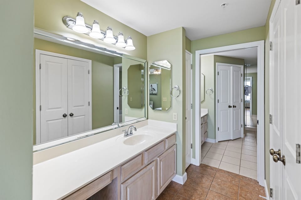 Step into your serene bathroom retreat with soft sage walls, elegant vanity lighting, and spacious countertops perfect for your morning routine.