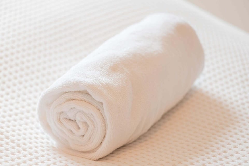 A neatly rolled white towel placed on a bed or countertop, adding a touch of luxury.