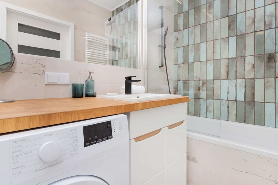 A view of the bathroom vanity with a sink, mirror, and toiletries, set against a tiled wall.