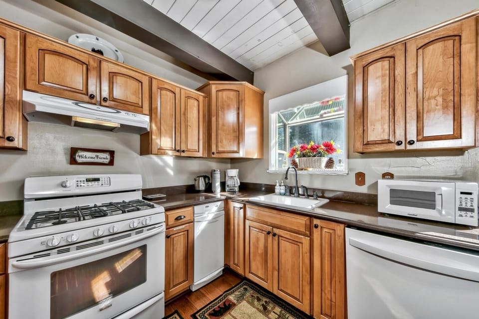 Your fully equipped kitchen awaits with warm wood cabinets, modern appliances, and charming exposed beams overhead.