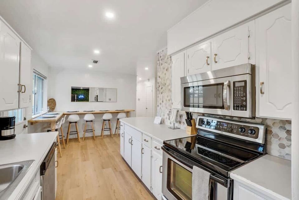 Fully equipped kitchen with modern appliances and a spacious layout, opening to a large breakfast bar for easy group dining.