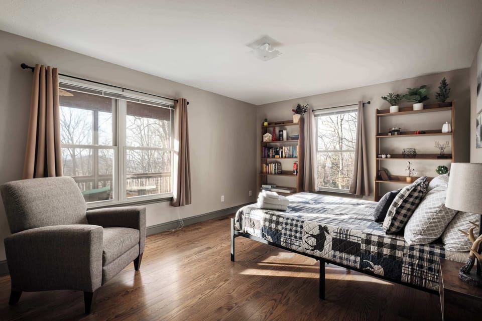 Bright & Cozy Bedroom – A spacious bedroom with large windows, a comfortable bed, and bookshelves for a homey touch.