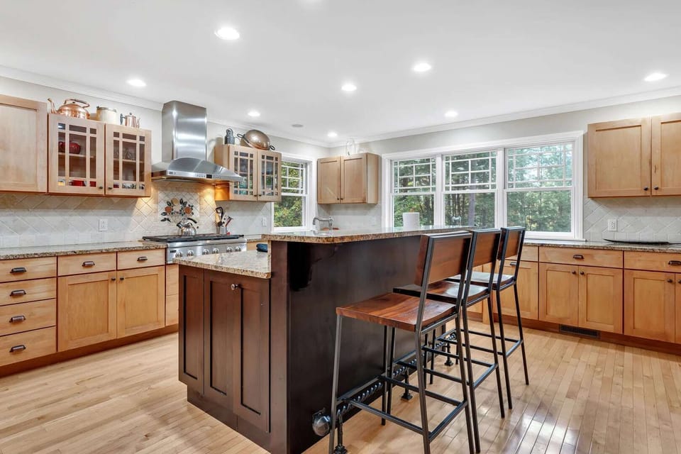 Kitchen island with bar seating for three, stainless appliances, and large windows