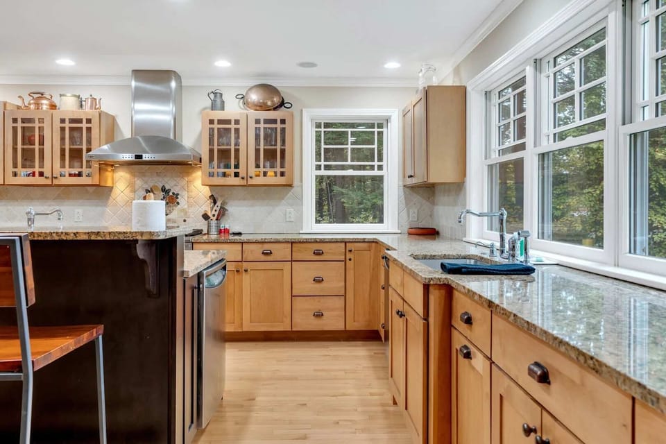 Kitchen with glass-front cabinets, stainless hood, and views of the surrounding trees