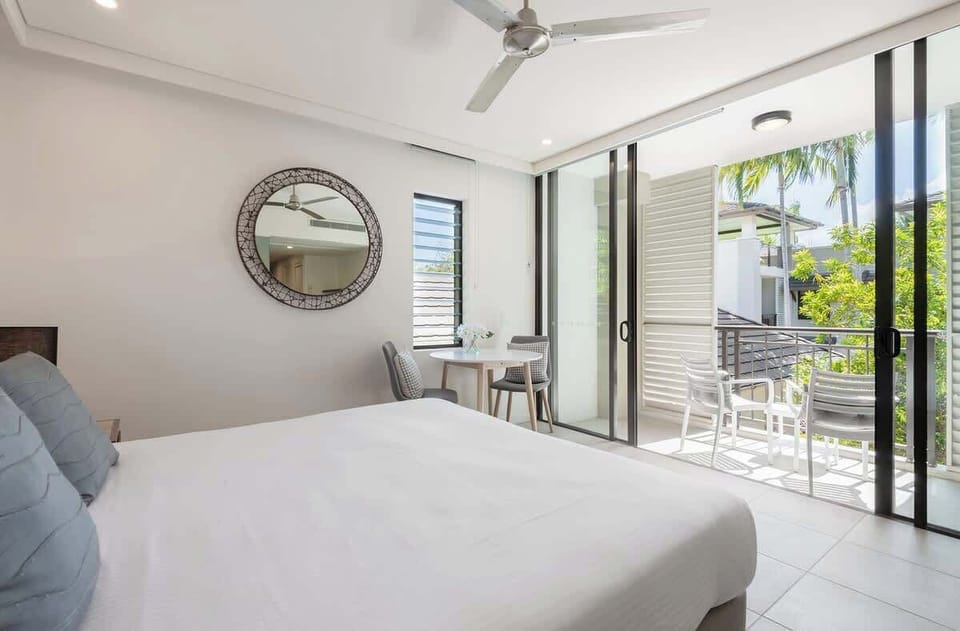 The luxe studio highlights a king-sized bed and extends to a private balcony with seating overlooking the pool.