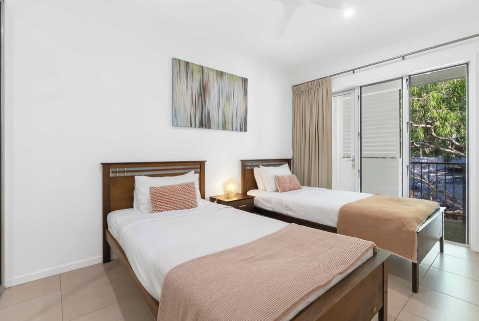 Rest easy in bedroom three, featuring two single beds, a ceiling fan and cooling—plus access to a compact balcony.