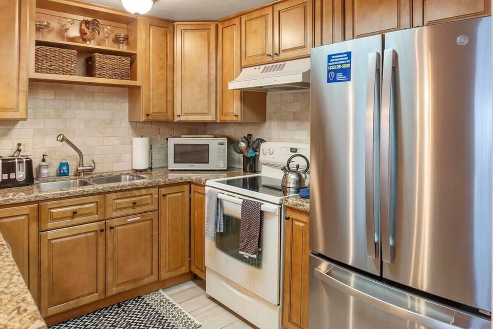 The fully updated kitchen boasts granite countertops, a tile backsplash and floors, a roomy stainless steel refrigerator, and a kitchen bar with seating for four.