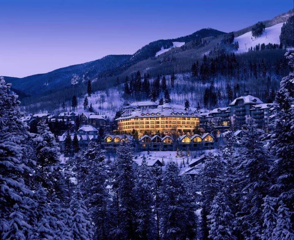 Experience a winter wonderland as the lodge glows warmly against a backdrop of snow-covered peaks.
