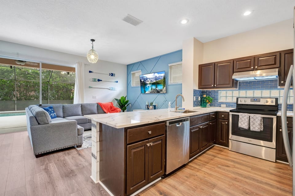 Our open layout seamlessly connects the kitchen to the living and dining area, while offering views of the sparkling pool through large custom sliding glass doors. 