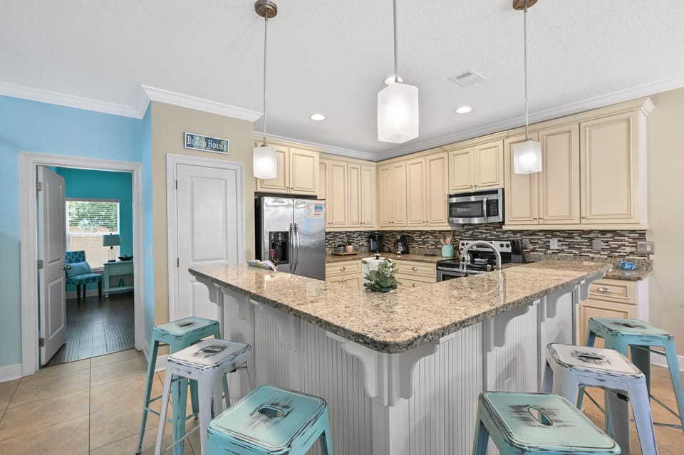Your fully equipped kitchen features granite countertops, stainless appliances, and cheerful turquoise accents perfect for preparing memorable meals together.
