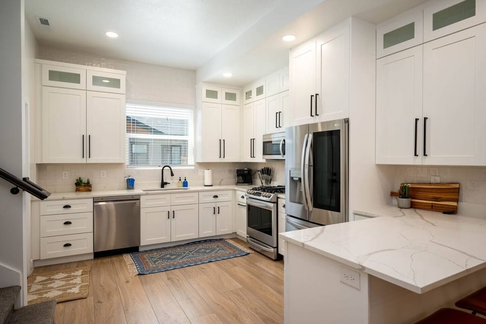 The gourmet kitchen features an island with seating and is equipped with stainless steel appliances, including a microwave, gas stove, and spacious refrigerator.