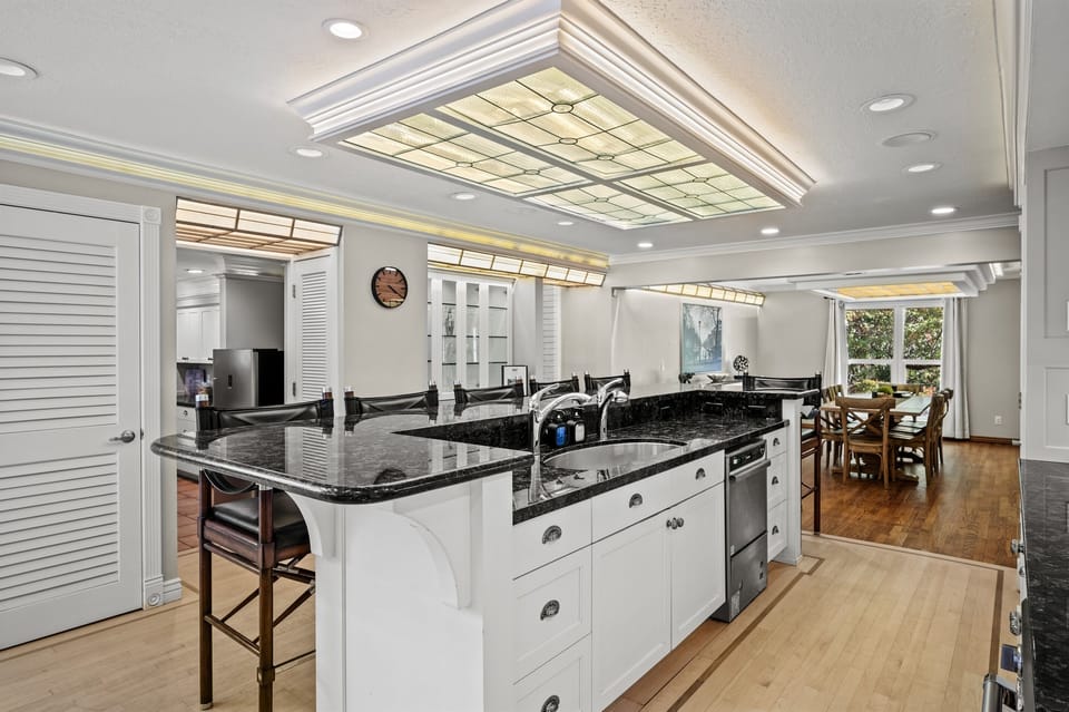 The gourmet kitchen features an island with seating for six and is equipped with stainless steel appliances, including a microwave, gas stove, and spacious refrigerator.