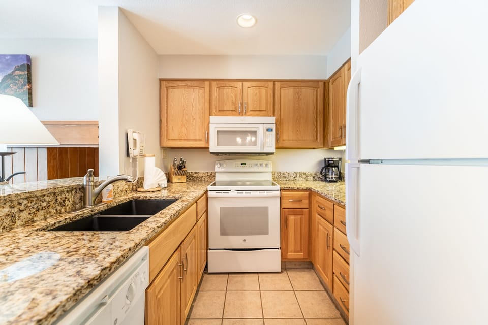Your fully equipped kitchen features granite counters, modern appliances, and warm wood cabinets—perfect for preparing meals during your stay.