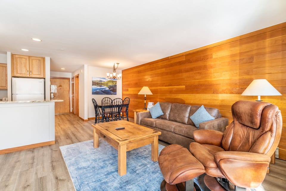Relax in your cozy living space featuring rich wood accents, plush leather seating, and an open kitchen perfect for home-cooked meals.