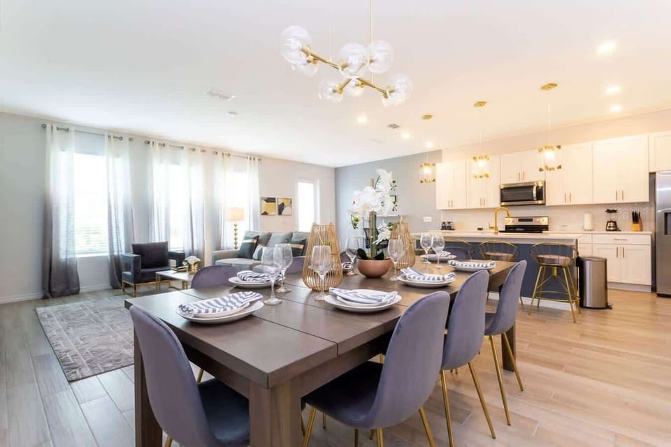 Bright and breezy living/dining flows into the chef-ready kitchen-8-seat table, cozy lounge, and a navy island with glam gold details for easy entertaining.