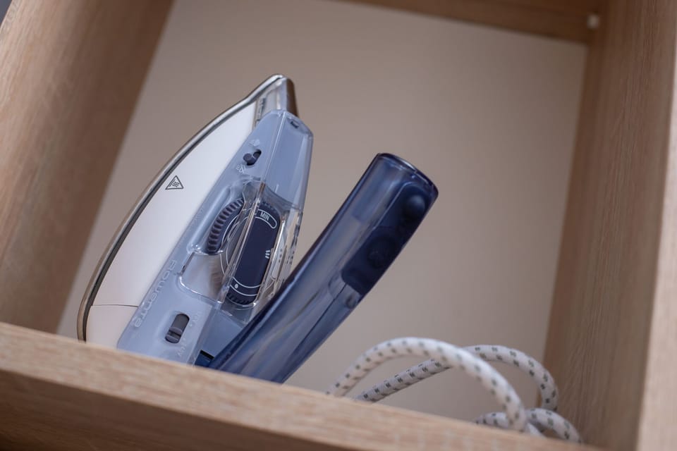 A wooden shelf containing a neatly placed iron.

