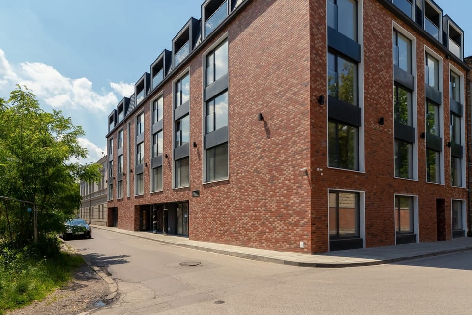 The exterior of a modern brick building with large glass windows and a neatly paved pathway.
