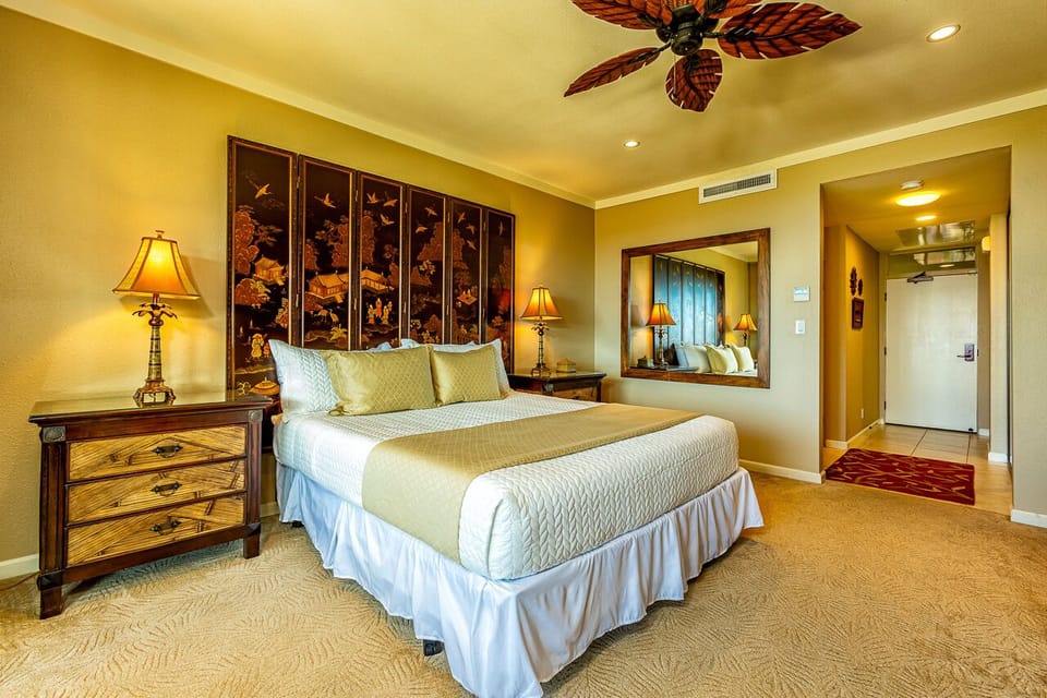 Drift off beneath tropical ceiling fan blades in your elegantly styled bedroom, where plush linens and warm island decor create your perfect retreat after days spent exploring.