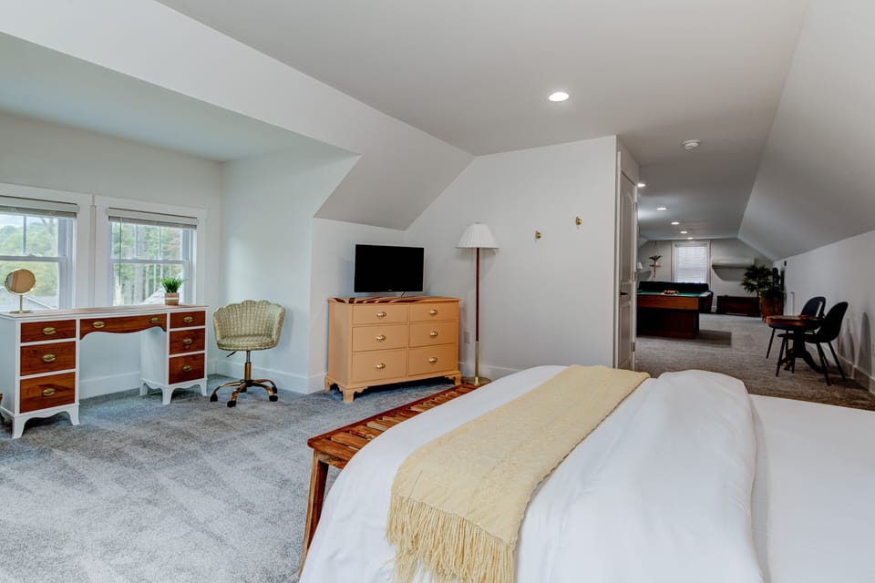 Spacious upstairs bedroom with a queen bed, dresser, and peaceful natural light