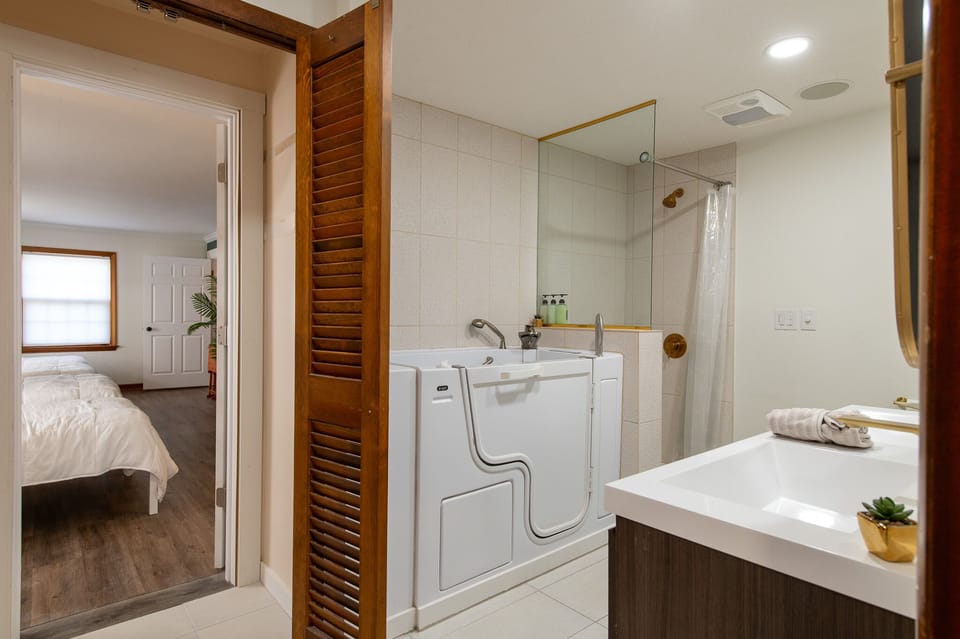 Step into your private spa-like bathroom featuring a luxurious walk-in tub and rainfall shower, complete with fluffy towels.