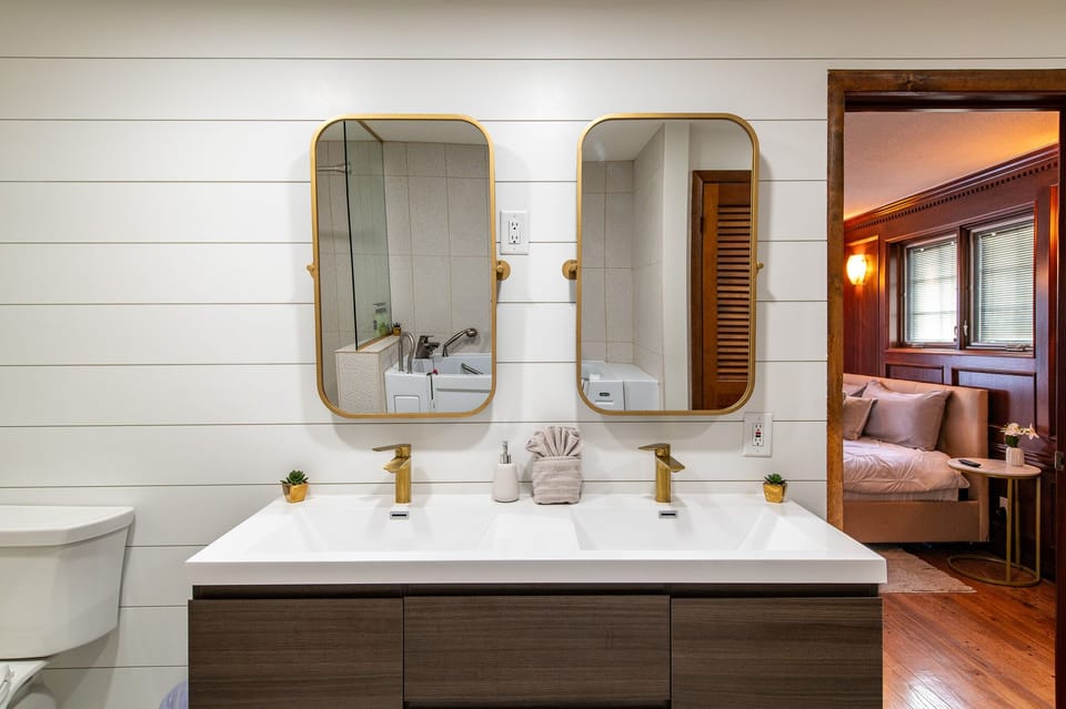 Step into your luxurious bathroom featuring dual vanity sinks with golden fixtures and modern brass-framed mirrors on crisp white shiplap walls.