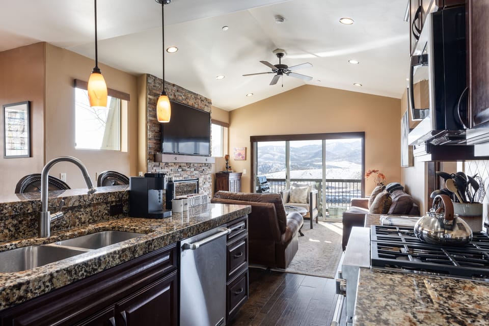 - Modern kitchen flows into living room with mountain views  
- Granite island with sink and stainless steel appliances  
- Open layout ideal for family gatherings and relaxing