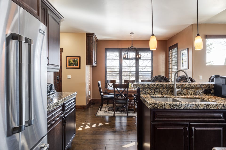 - Kitchen with stainless steel appliances and granite tops  
- Pendant lights brighten the space with warm tones  
- Dining area nearby offers seating with mountain views