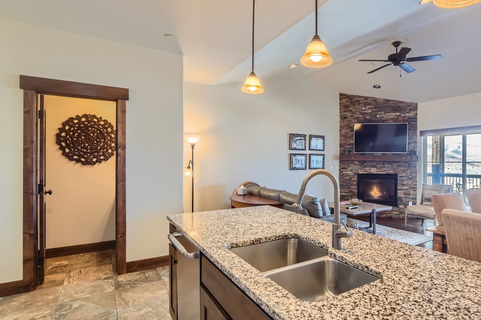 - Bright open kitchen with dual sink island and pendant lighting overhead  
- Living area with fireplace and mountain views right from the counter  
- Spacious layout perfect for family cooking and entertaining