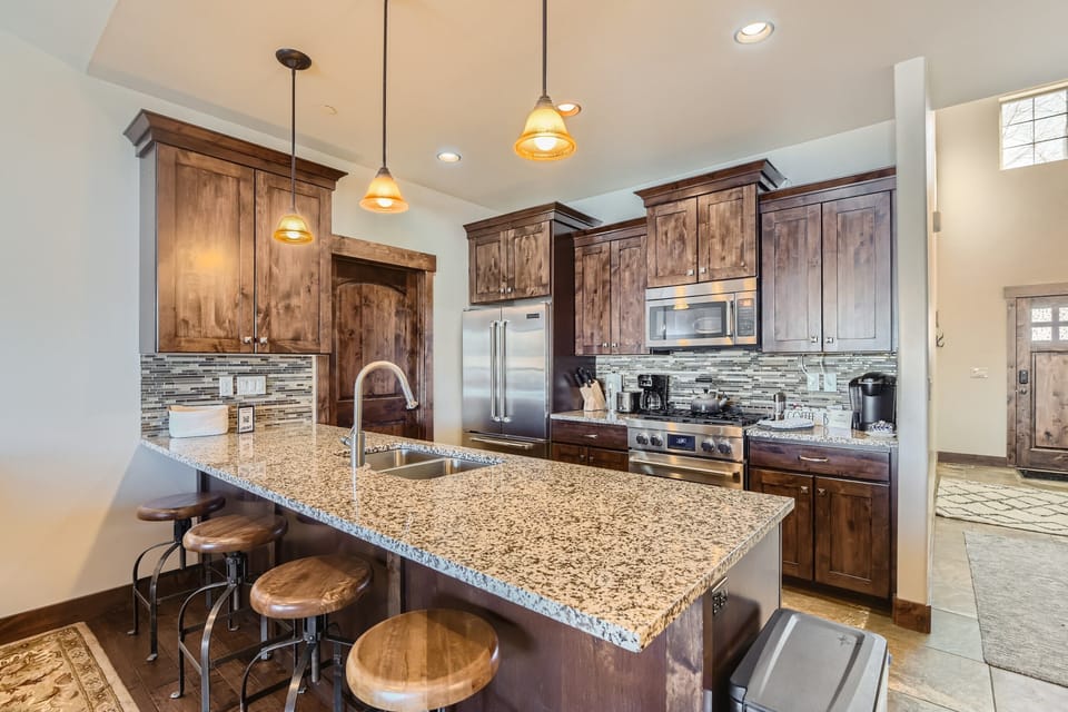 - Fully equipped kitchen with stainless steel appliances and granite counters  
- Wooden cabinetry and modern backsplash create a rustic yet polished look  
- Breakfast bar with stools offers a perfect spot for casual dining