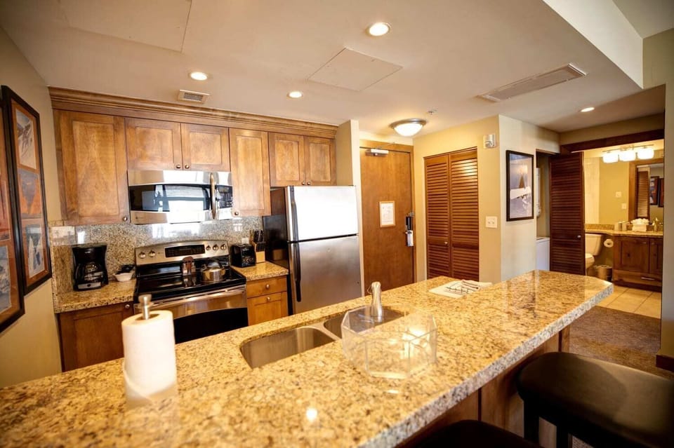 Full kitchen with granite countertops, stainless steel appliances, and bar seating for casual dining.
