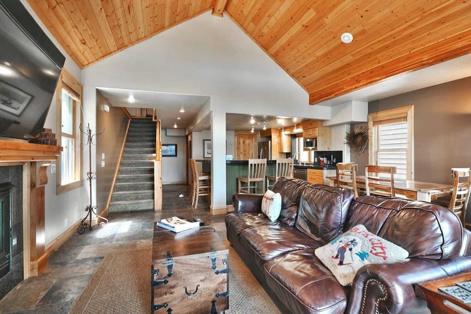 - Cozy living room with leather sofa and fireplace  
- Open layout connects seamlessly to kitchen and dining  
- Warm wood accents create a true mountain retreat feel