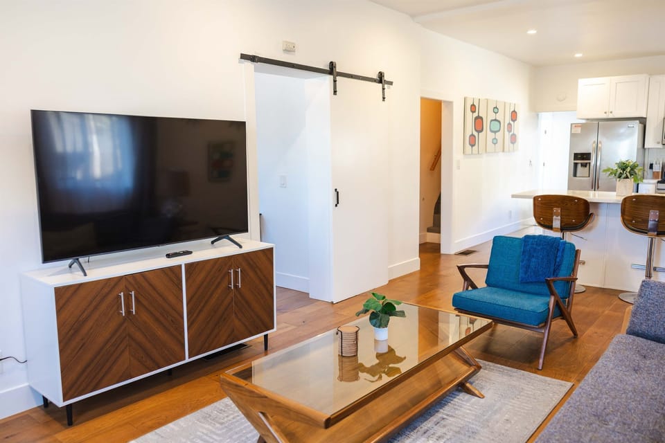 Living room with couch, chair, side table, coffee table, arcade game for 2 and television connected to the internet.