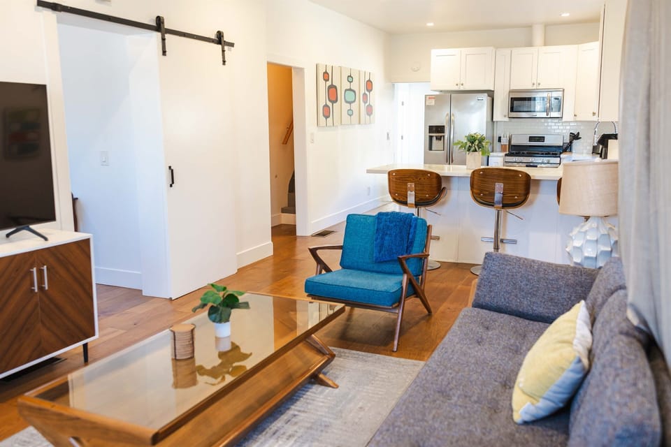 Living room with couch, chair, side table, coffee table, arcade game for 2 and television connected to the internet.