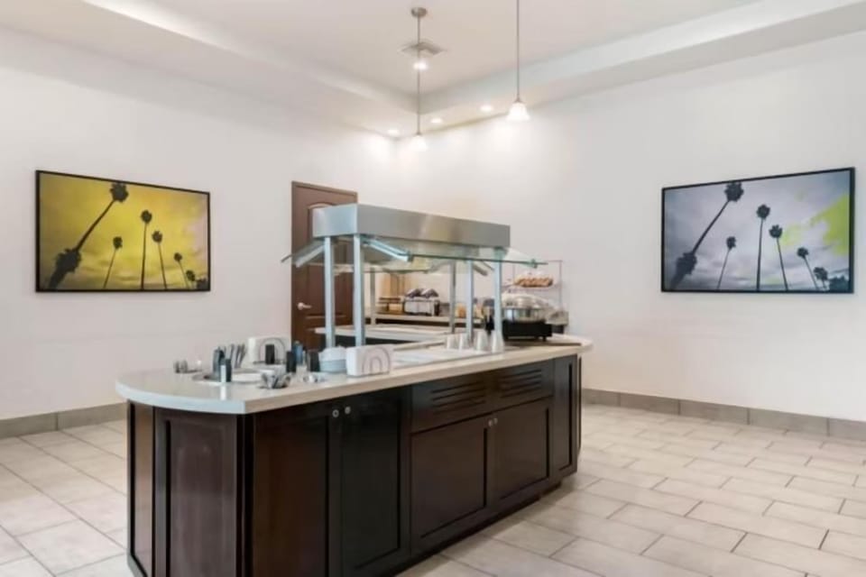 Breakfast buffet station with stainless steel chafing dishes and tropical palm artwork