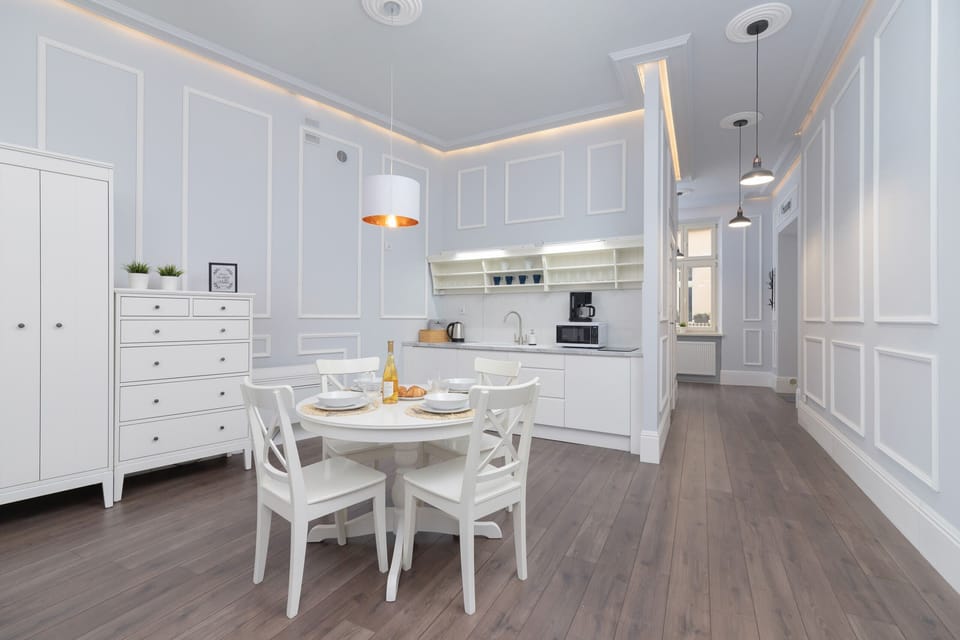 A complete view of the open-plan room, featuring a dining table, kitchen, and sleeping area.
