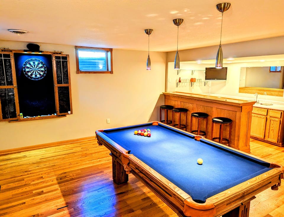 Game room on lower level w/ pool table, dart board, Smart TV, & wet bar.