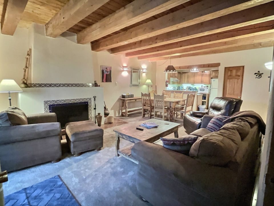 Living room with overstuffed leather furniture and classic wood burning fireplace fire tools and fuel provided