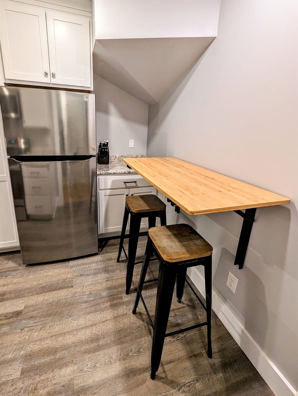 Dining table is wall-mounted for efficient use of space, and can be folded away when not in use. Two bar stools.