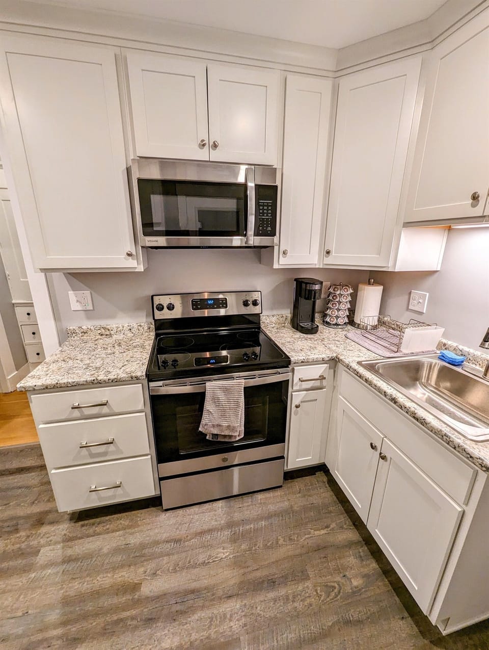 Stocked kitchen with microwave, electric range, refrigerator, coffee maker, and various utensils, plates, bowls, cups, etc.