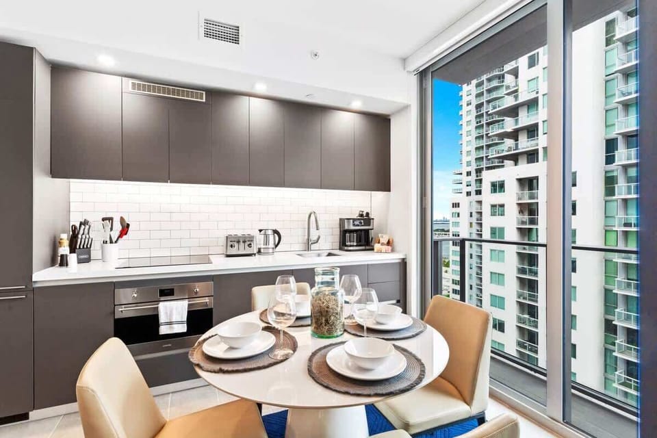Seamless Elegance: Revel in the harmonious design of your dining area, seamlessly connected to an open kitchen, creating a space where relaxation meets culinary creativity, all against the backdrop of Miami's dynamic scenery. #ElegantLiving #MiamiVib