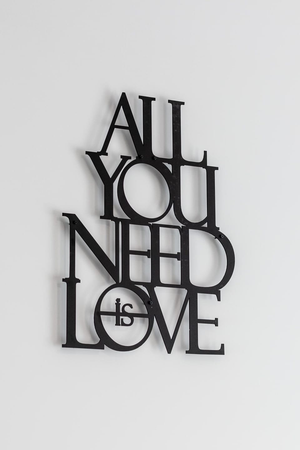 A motivational wall art piece that reads "ALL YOU NEED IS LOVE" in a minimalist black font.

