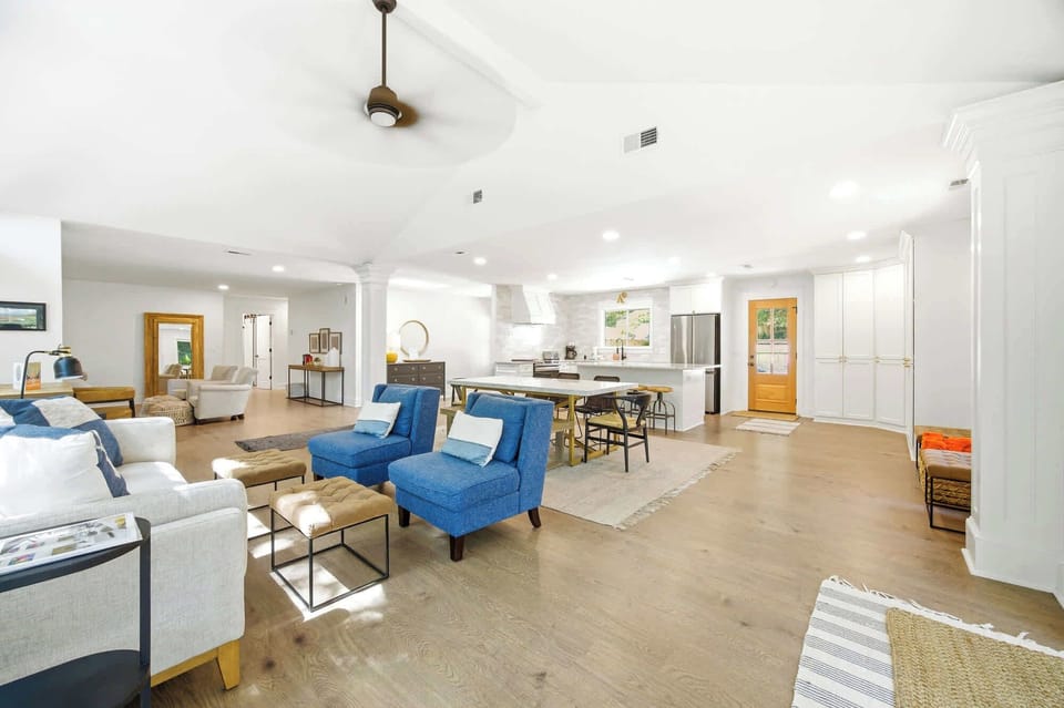 Cerulean armchairs bring a splash of coastal color to this airy open floor plan, where vaulted ceilings and honey-toned wood floors create a sense of calm. Bright surroundings and soft textures make this the perfect hub for gathered conversation.