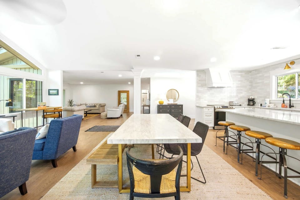 Creamy stone surfaces and warm wood accents anchor this airy open floor plan. Soft dayglow fills the room, highlighting the blend of textures and inviting comfortable conversation from the sleek kitchen to the cozy lounge.